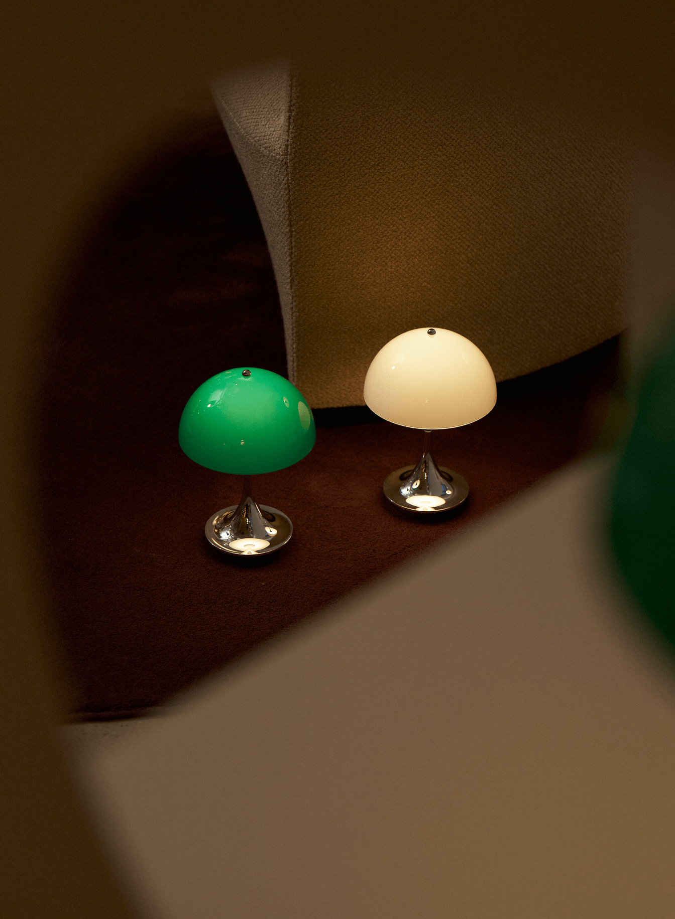 Two Panthella table lamps in Original colours beside lounge chair, © 2025 Louis Poulsen.