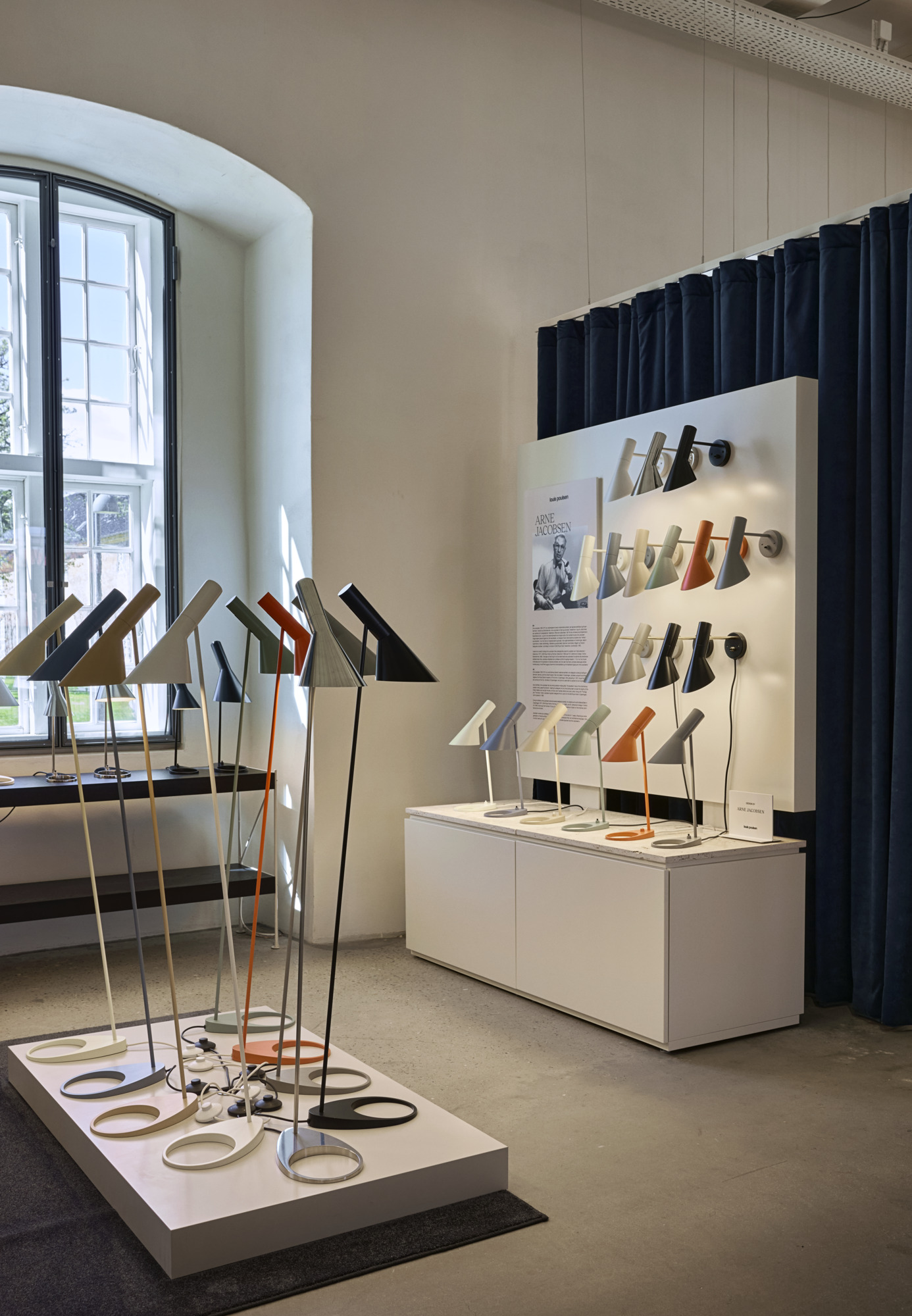 AJ table, floor and wall lamps in multiple colours displayed inside the Louis Poulsen Copenhagen showroom, © 2025 Louis Poulsen.