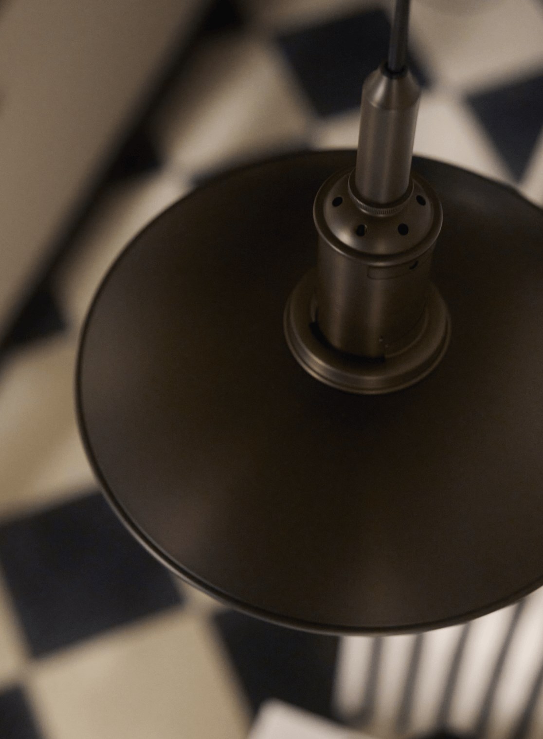 PH Aged Brass pendant lamp in modern interior with geometric flooring, © 2025 Louis Poulsen.