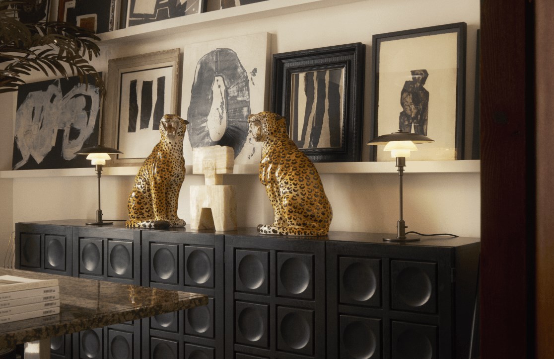 Two PH Aged Brass Opal table lamps beside leopard sculptures in stylish gallery space, © 2025 Louis Poulsen.