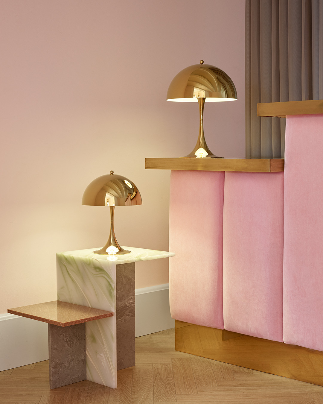 Panthella 320 and 250 brass table lamps on a marble and wood side table, © 2025 Louis Poulsen.