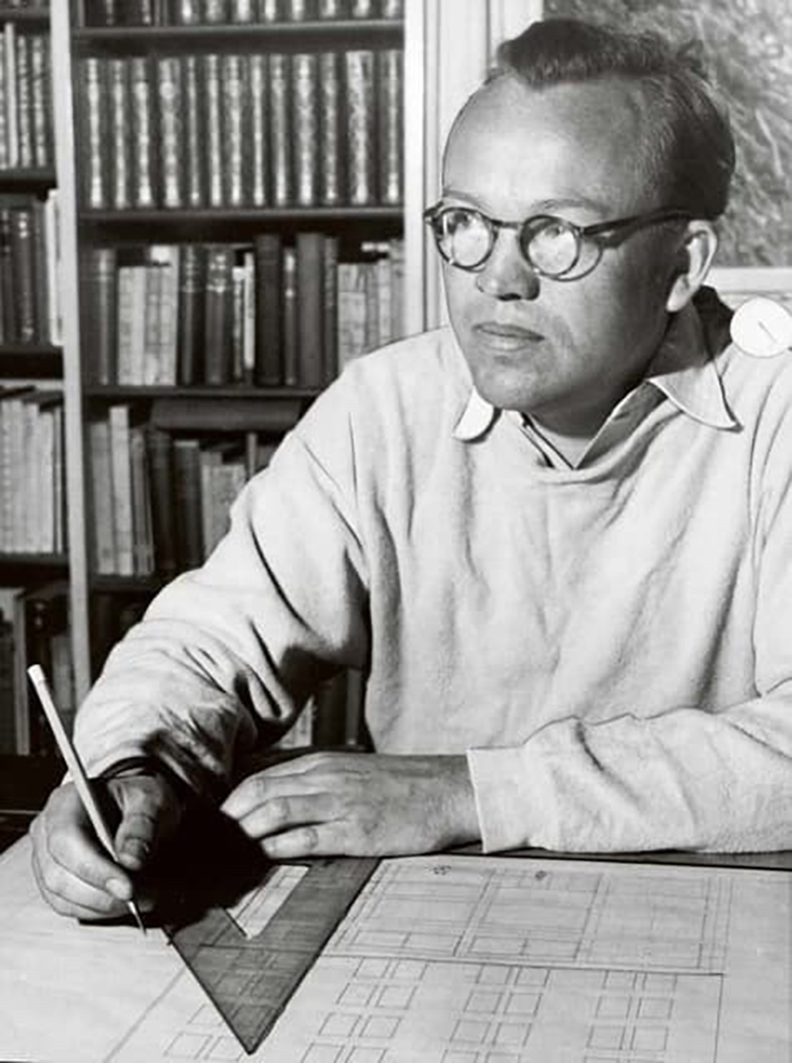 Finn Juhl sketching architectural plans at a desk, © 2025 Louis Poulsen.
