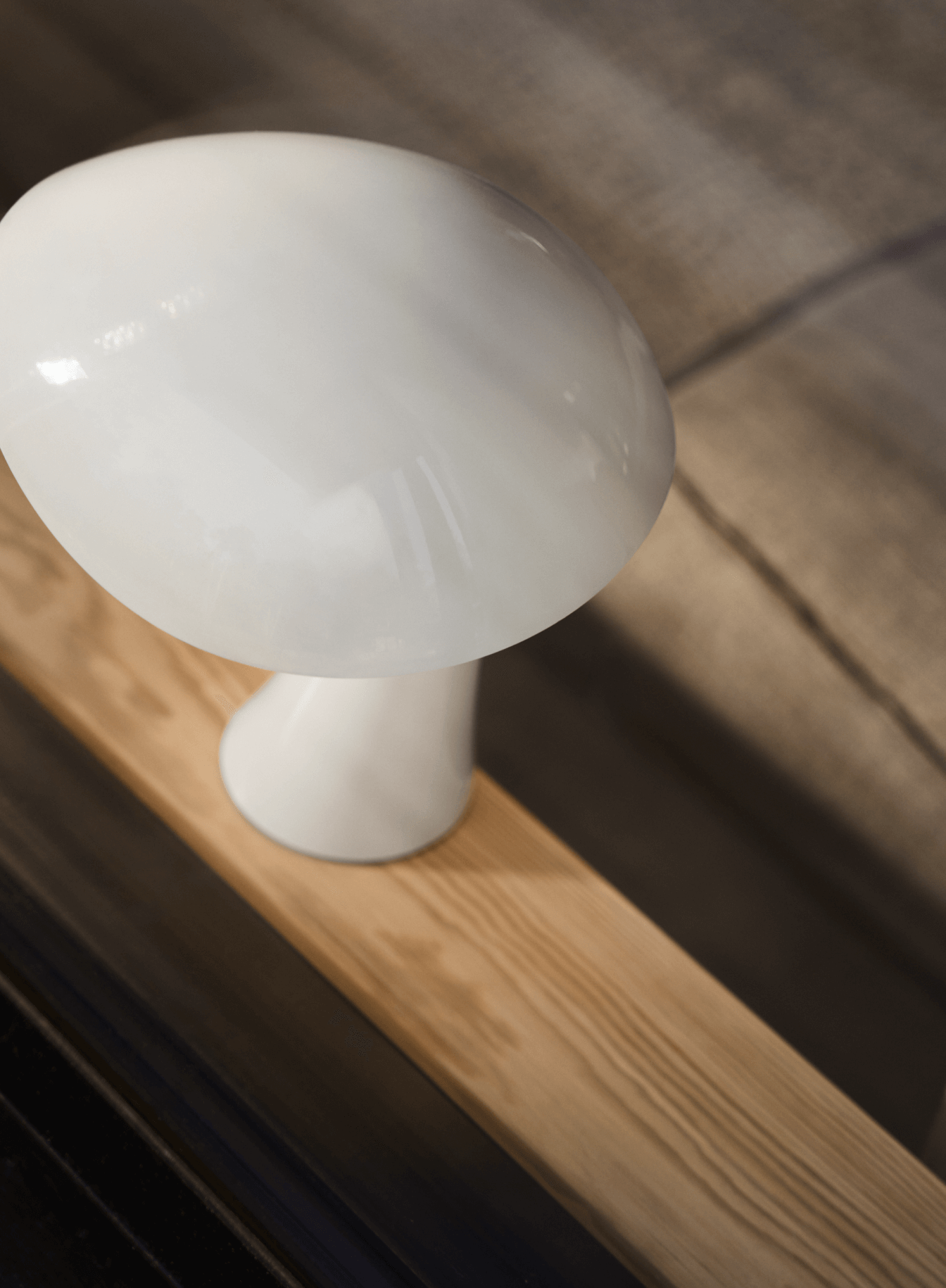 "Close-up of a white Rumee portable lamp, with soft lighting, placed on a wooden surface, © 2025 Louis Poulsen.