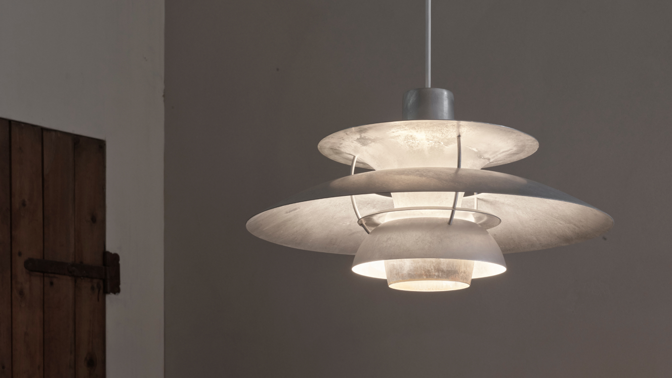 PH 5 Retake pendant casting soft light in a simple interior with wooden door, © 2025 Louis Poulsen.