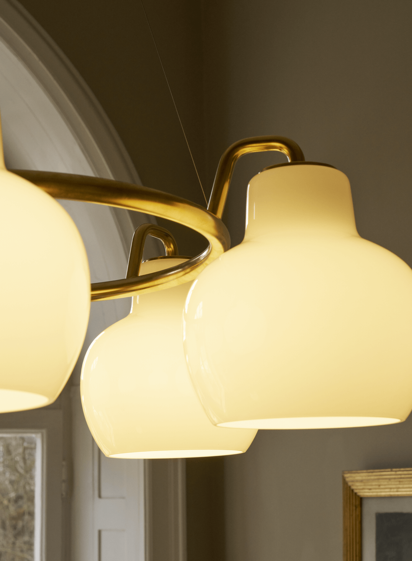 VL Ring Crown pendant with brass frame and opal glass glowing in interior, © 2025 Louis Poulsen.